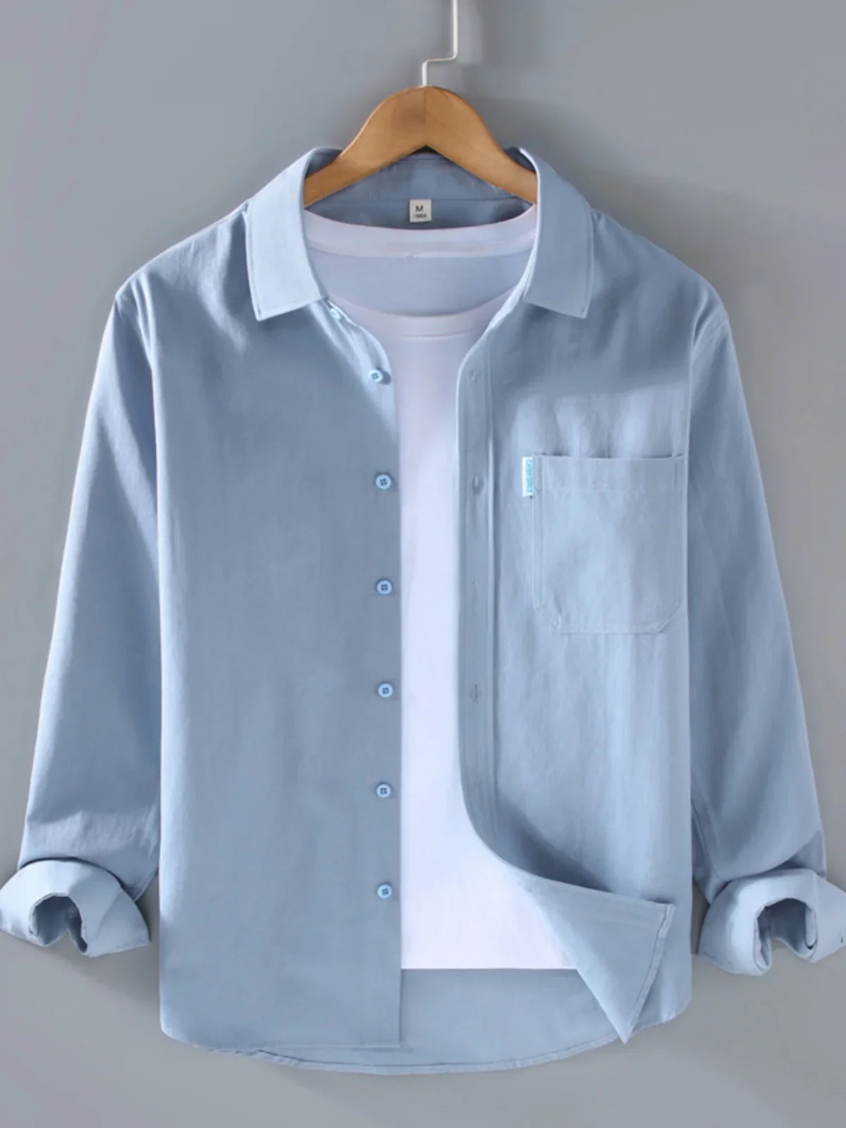 Spring solid color long sleeve button-up shirt hanging on a hanger.