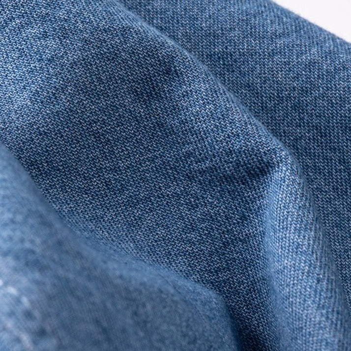 Close-up view of soft cotton fabric texture from a business casual denim shirt.
