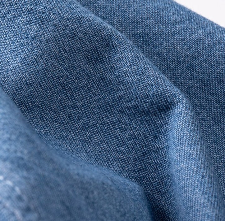 Close-up view of soft cotton fabric texture from a business casual denim shirt.