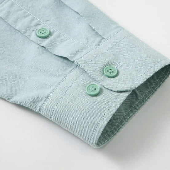 Close-up of a light mint green shirt sleeve showing the buttoned cuff and matching buttons on a white background.