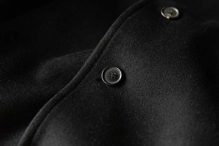 Close-up view of a single breasted trench coat button in black fabric.