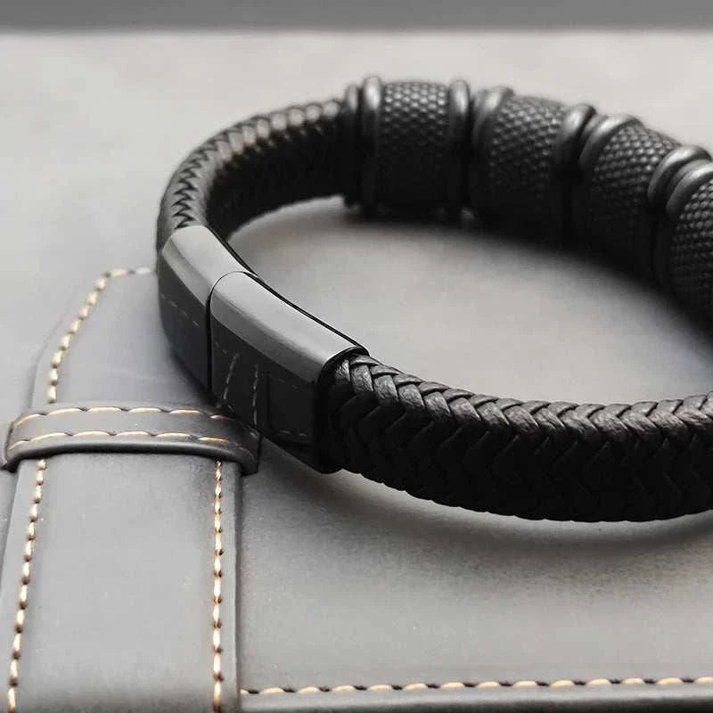 Stainless steel leather bracelet with PU detailing on a gray surface.