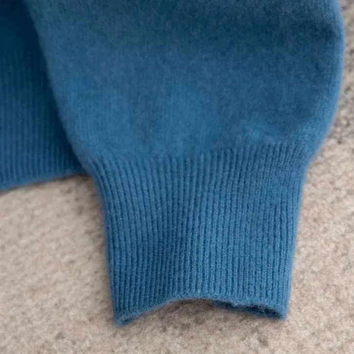 Close-up of a blue business wool turtleneck sweater sleeve on a beige background.