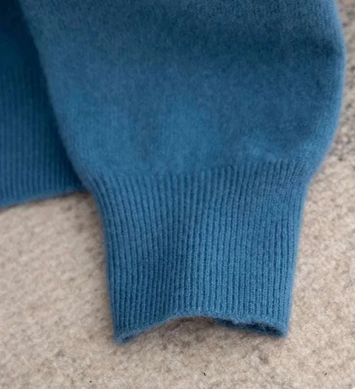 Close-up of a blue business wool turtleneck sweater sleeve on a beige background.