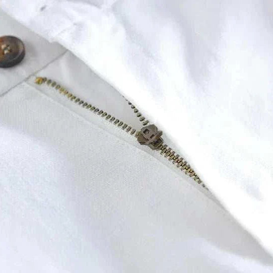 Close-up view of straight oversize trousers zipper and button detail in white polyester.