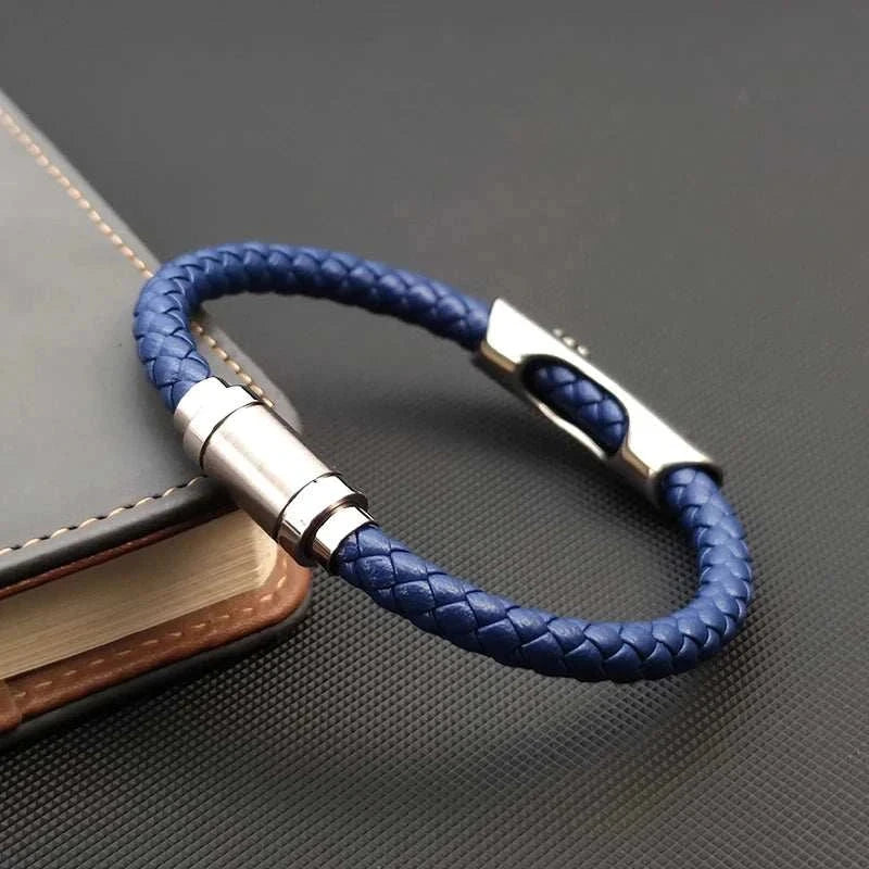 Leather bracelet with stainless steel cross on notebook surface.