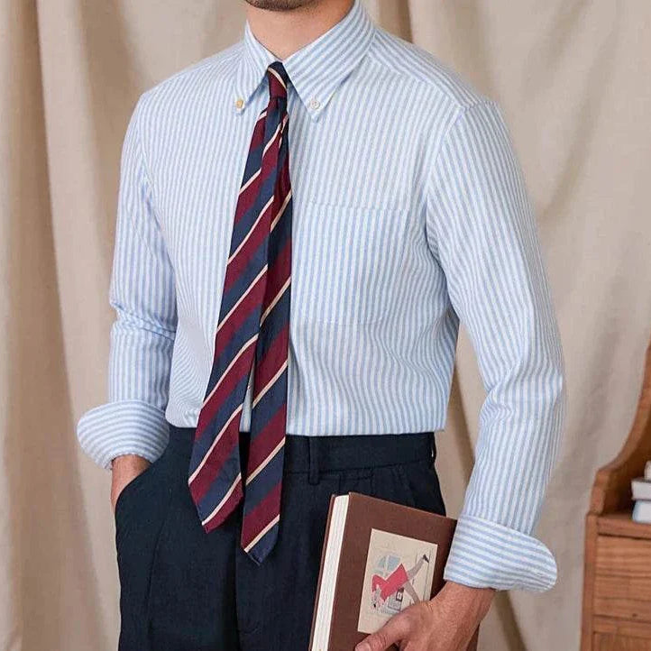Oxford style casual cotton shirt for men, blue striped pattern, button-down collar, paired with a tie.