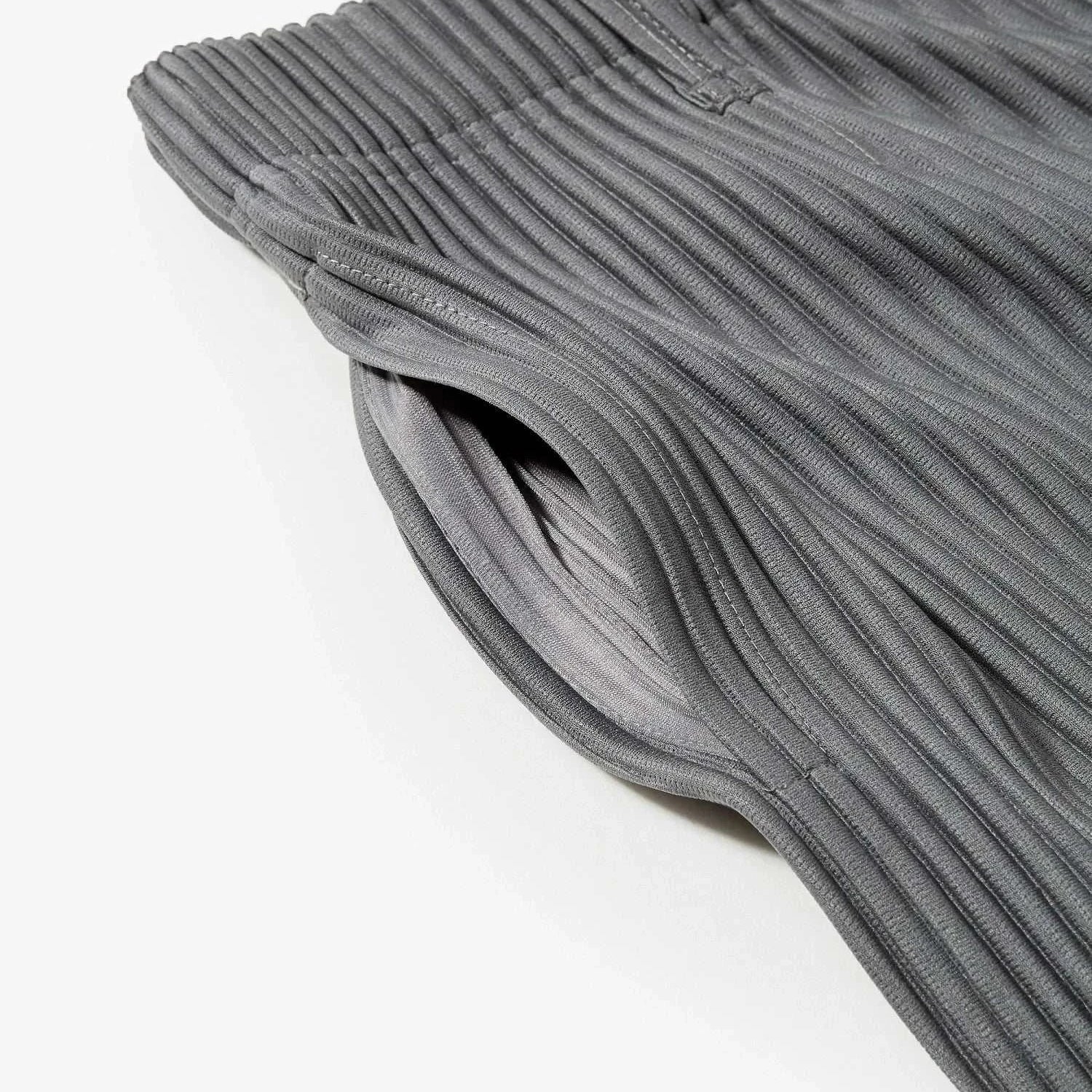 Close-up of gray baggy relaxed fit casual trousers with an elastic waistband and pleated design.