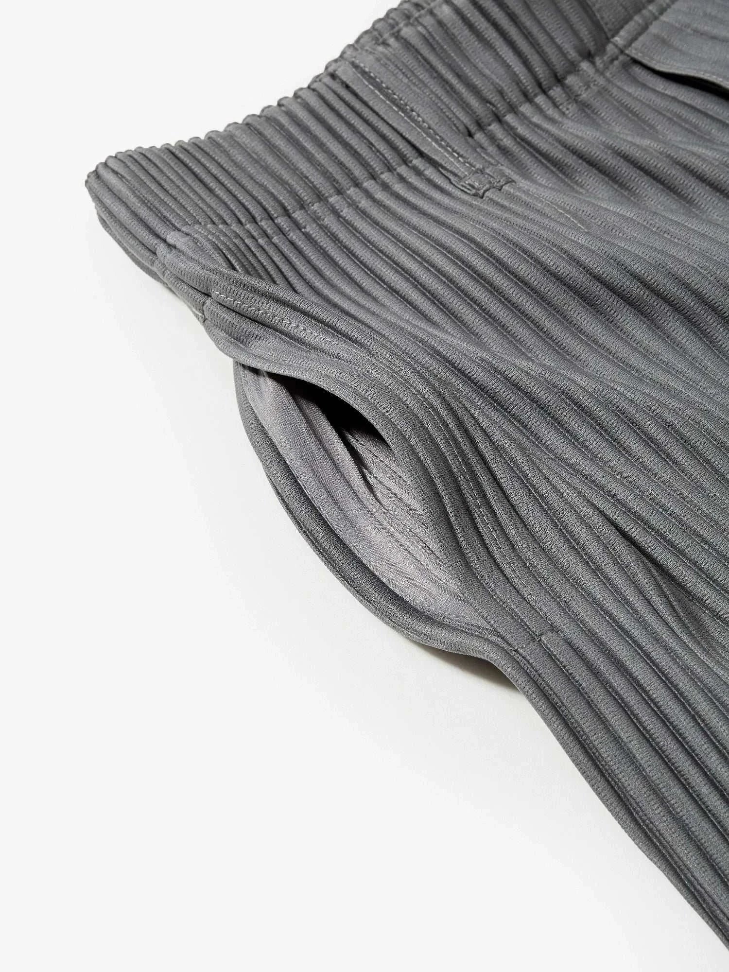 Close-up of gray baggy relaxed fit casual trousers with an elastic waistband and pleated design.