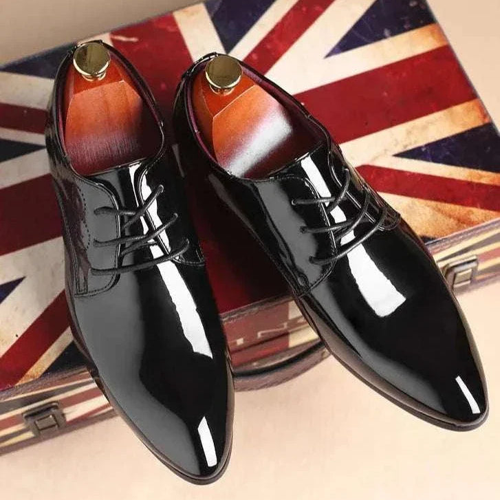 Brogue elegant shoes in glossy black finish on Union Jack background.