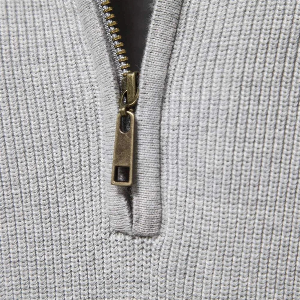 Close-up of zipper detail on high-collar autumn/winter sweater in gray fabric.