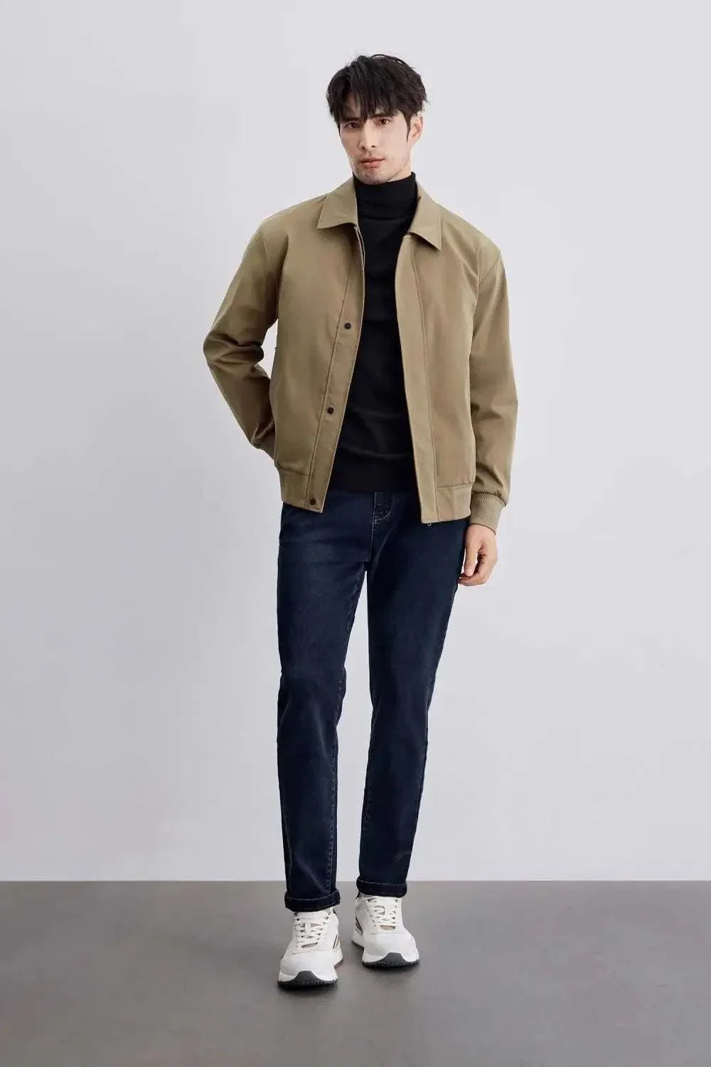 Man wearing Korean bomber winter jacket with black turtleneck and jeans.