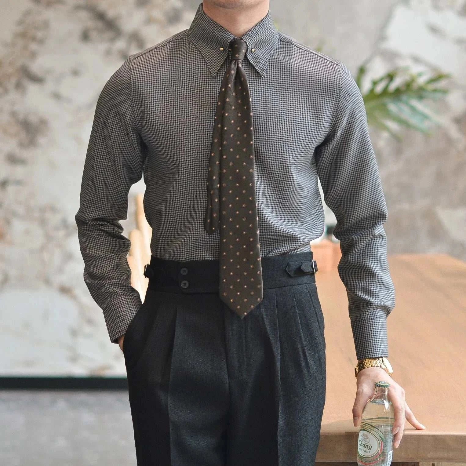 Man wearing an office tuxedo long-sleeve shirt paired with dark trousers and a patterned tie, standing indoors.