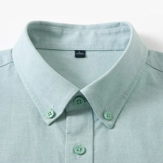 Close-up of a light mint green button-down shirt collar with matching buttons, shown against a plain white background.