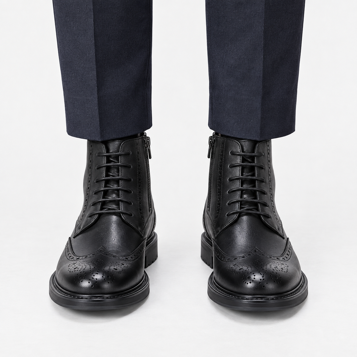 Leather wingtip boots with side zips in black, front view on a model