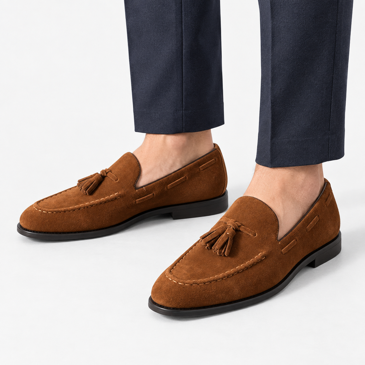 Suede tassel loafers with rubber soles in tan, side view on a model