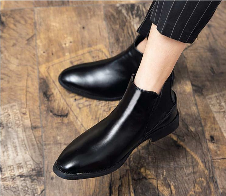 Black leather boots on wooden floor, worn with pinstripe pants.