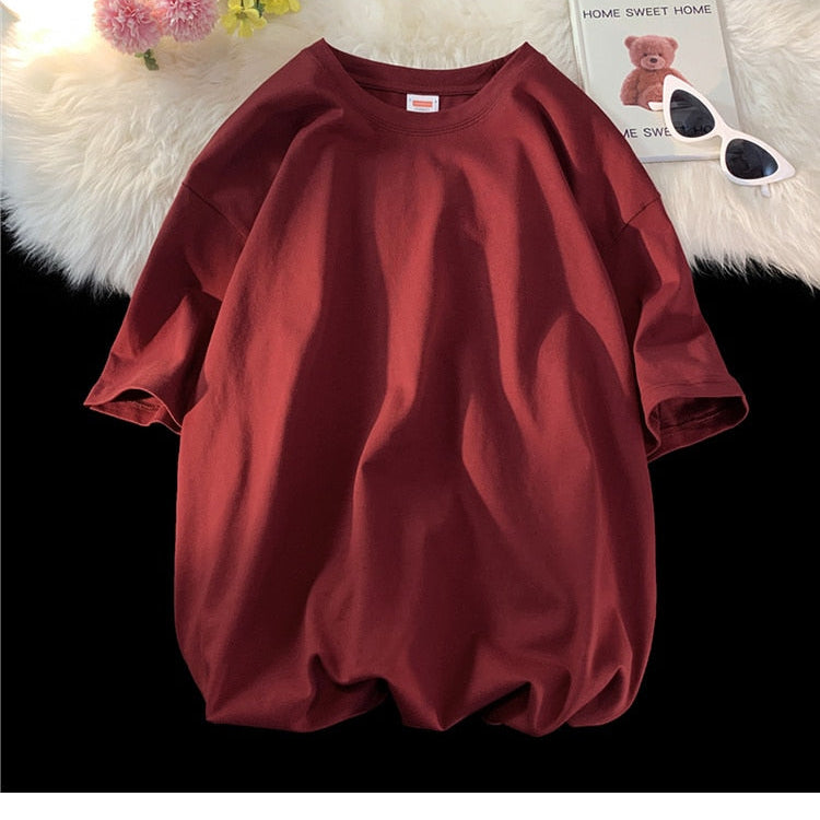 Antonios Oversized Casual Cotton T-Shirt in maroon on display surface with flowers and book.