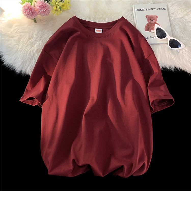 Antonios Oversized Casual Cotton T-Shirt in maroon on display surface with flowers and book.