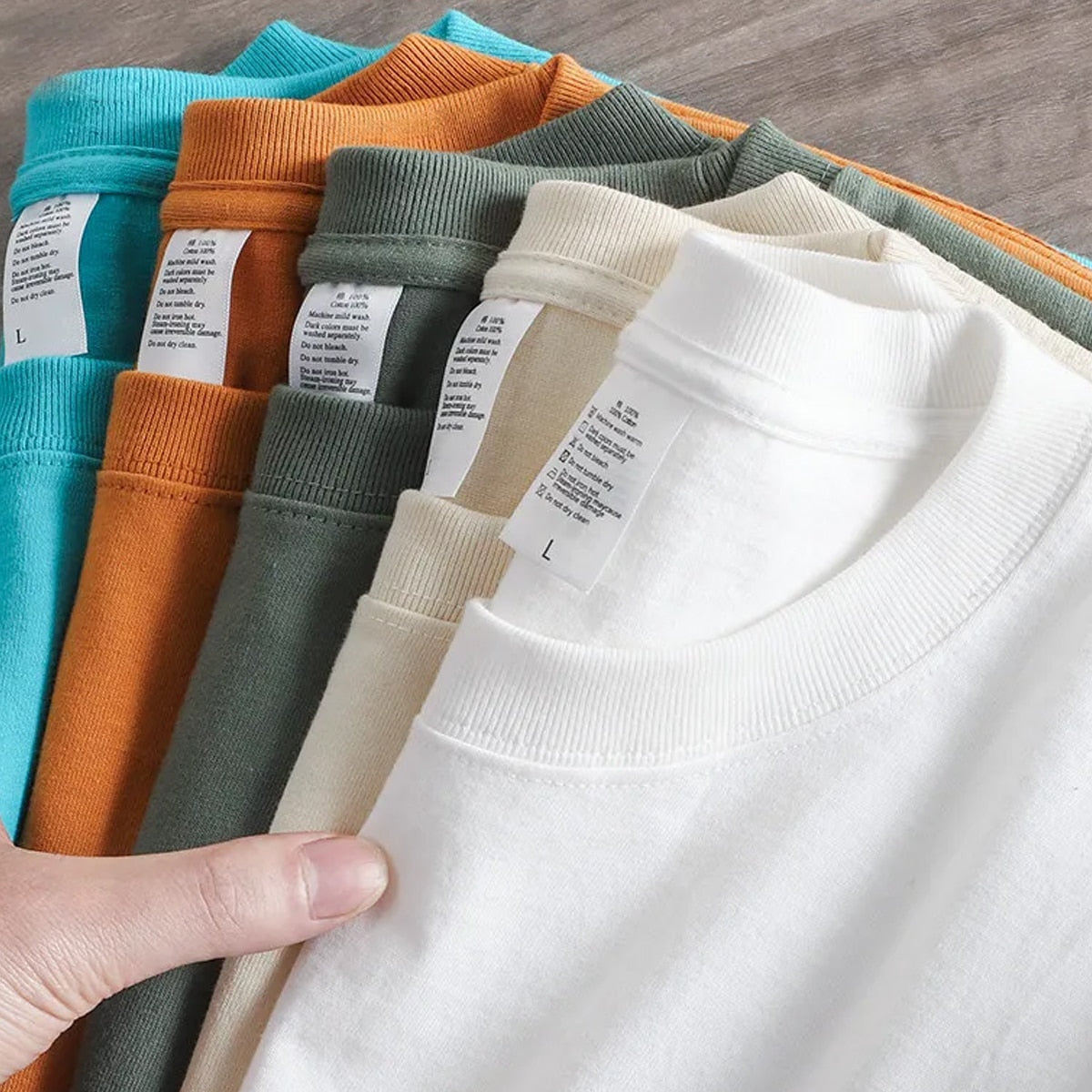 Assorted colors of Antonios Oversized Casual Cotton T-Shirts displayed in a hand, showcasing ribbed crew neck and soft fabric.