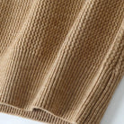 Close-up of a ribbed knit fabric in a warm camel brown color, showing the detailed texture and stitching.