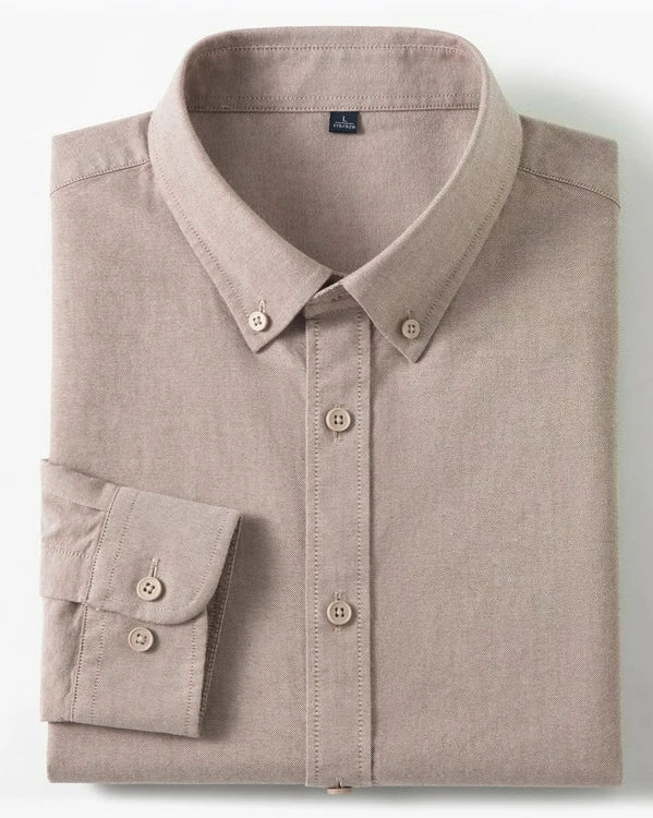 A folded long-sleeve button-up shirt in a light taupe-beige color, displayed on a clean white background with two small inset detail images on the right showing a cotton graphic and fabric texture.