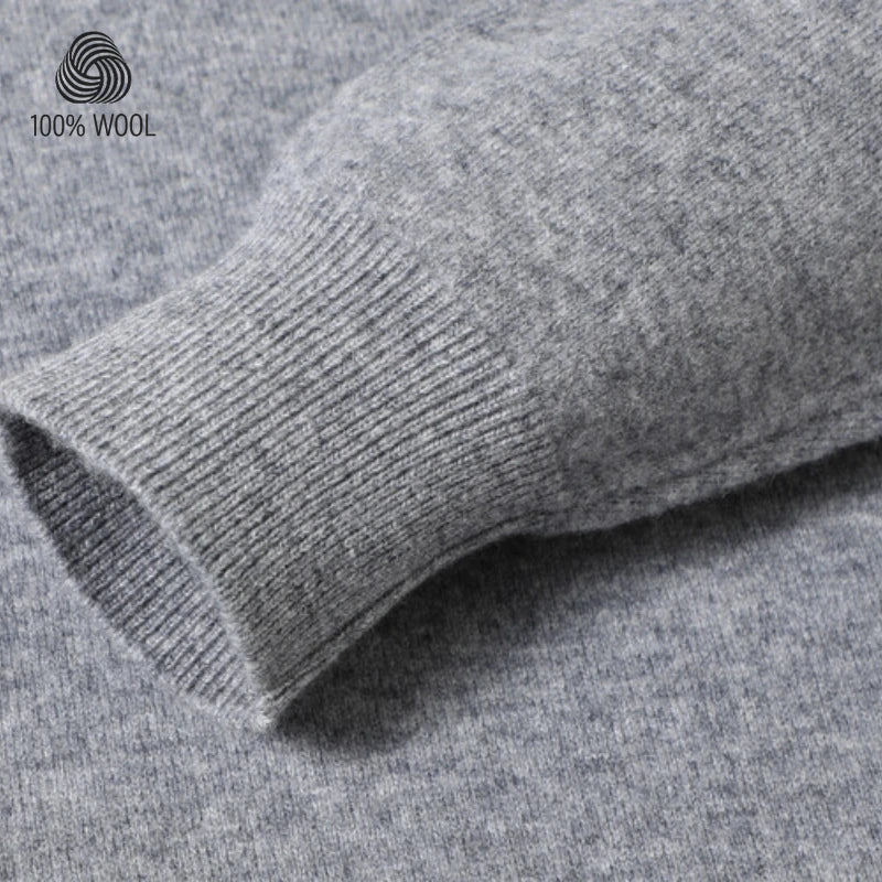 Close-up of a gray ribbed knit sleeve cuff with a heathered gray fabric body, showing texture and a small '100% WOOL' logo in the upper left corner.