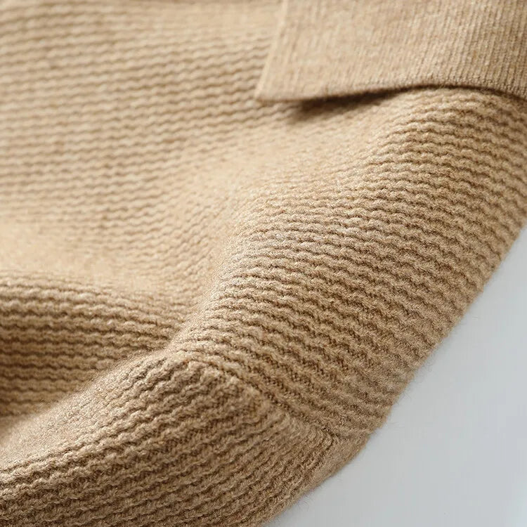 Close-up of a beige knitted sweater on a light gray background
