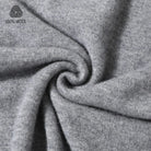 Close-up of heather gray wool fabric draped in a spiral, with a small '100% WOOL' logo in the upper left corner.