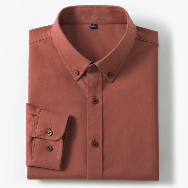 A folded long-sleeve button-down shirt in a muted terracotta or rust color, displayed on a clean white background.