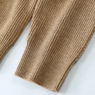 Close-up of a brown knitted sweater sleeve on a white background