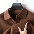 Brown knitted sweater on a hanger with a hand touching the fabric