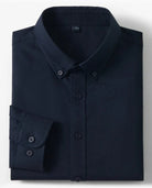 A folded dark navy long-sleeve button-down shirt with a pointed collar and button cuffs, shown on a light gray background with two small inset images on the right showing cotton and a fabric close-up.
