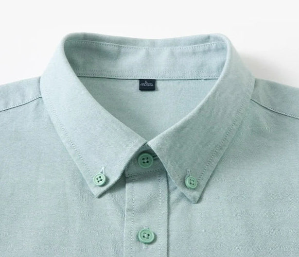Close-up of a light mint green button-down shirt collar with matching buttons, shown against a plain white background.
