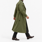 Long double breasted trench coat with a belt in olive green — side view on a male model