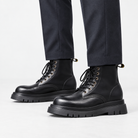 Black leather lace up combat boots in black, side view on a model