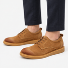 Distressed derby shoes with flexible soles in tan, side view on a model