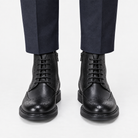 Leather wingtip boots with side zips in black, front view on a model