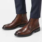 Leather wingtip boots with side zips in coffee, side view on a model
